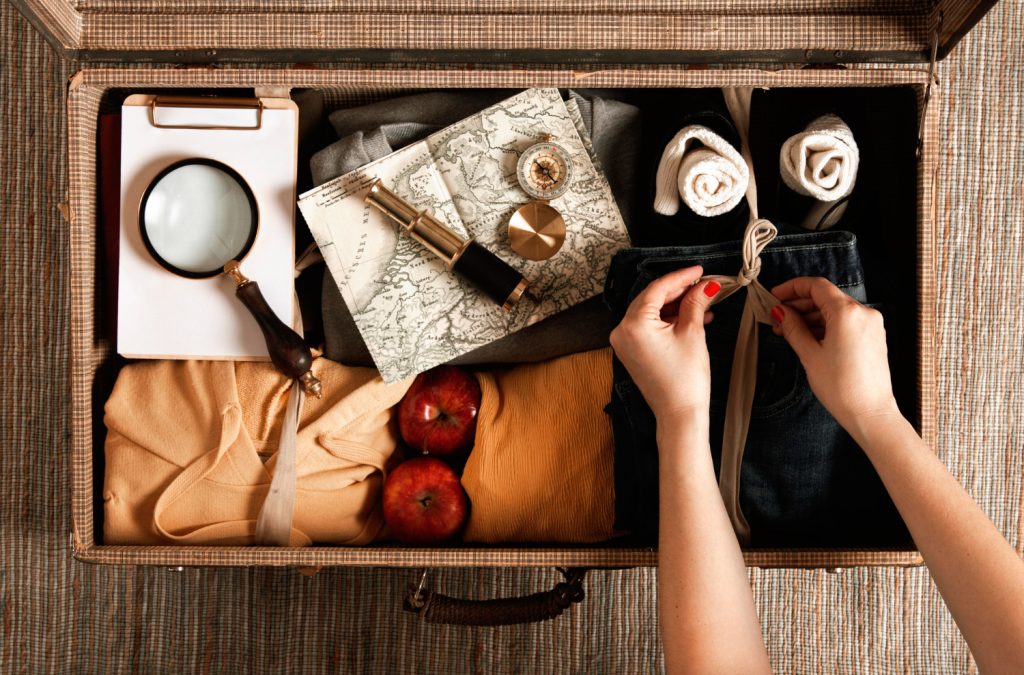 Top view vintage suitcase with a woman packing casual clothes
